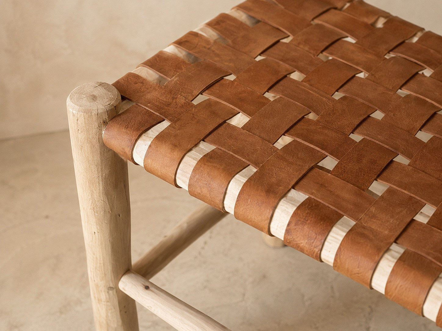 Détail du tressage en damier du cuir cognac sur le bois brut