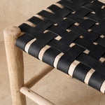 Détail du tressage en damier du cuir noir sur le bois brut