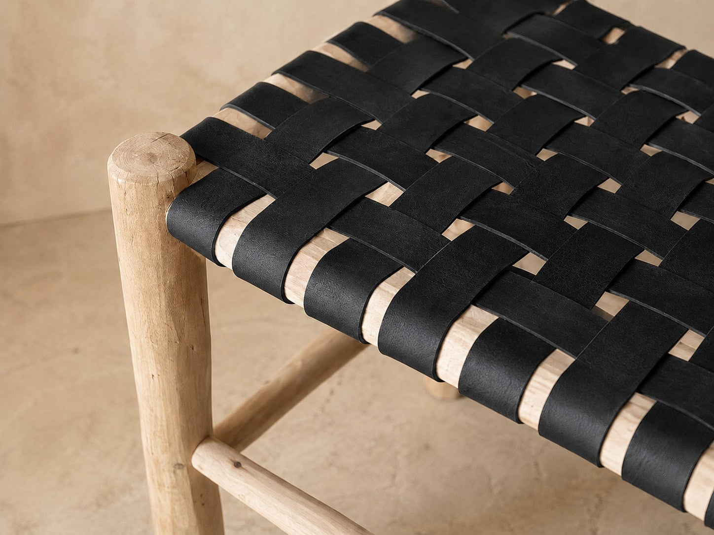 Détail du tressage en damier du cuir noir sur le bois brut