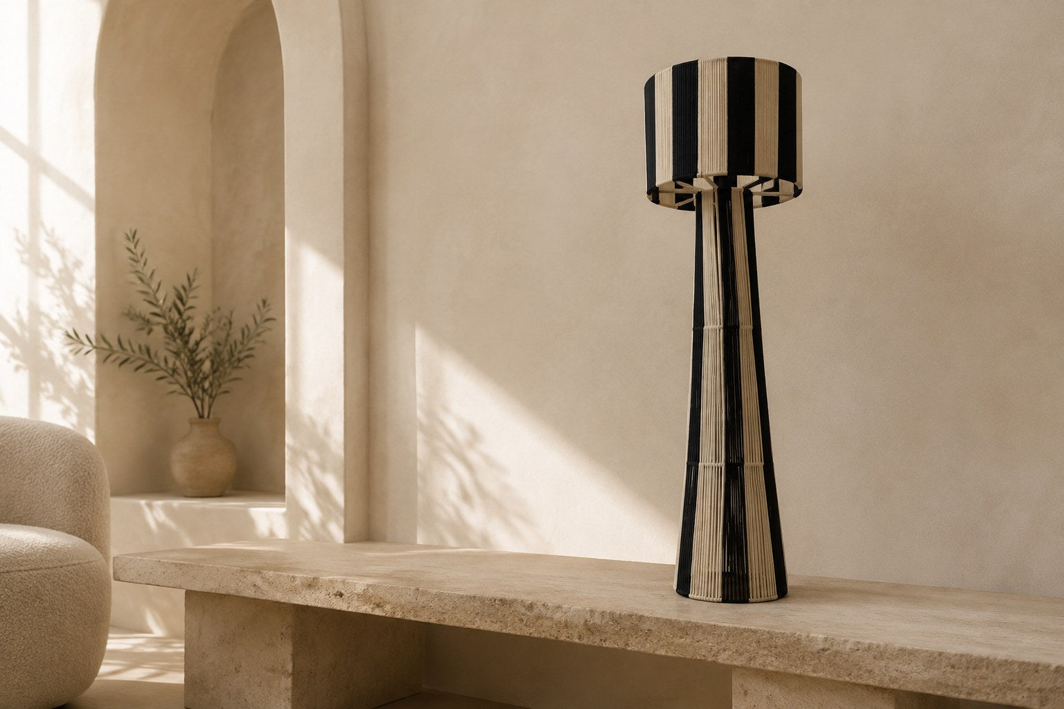 NARA, lampadaire tressé noir et écru posé sur une banquette en travertin