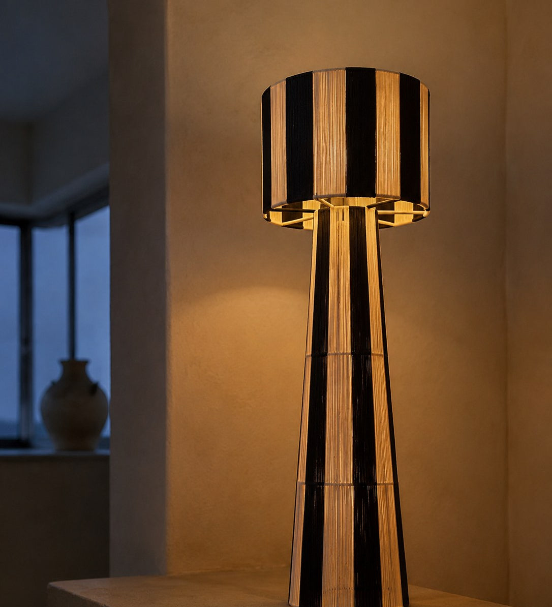 NARA, lampadaire tressé allumé, halo ambré dans une pièce sombre