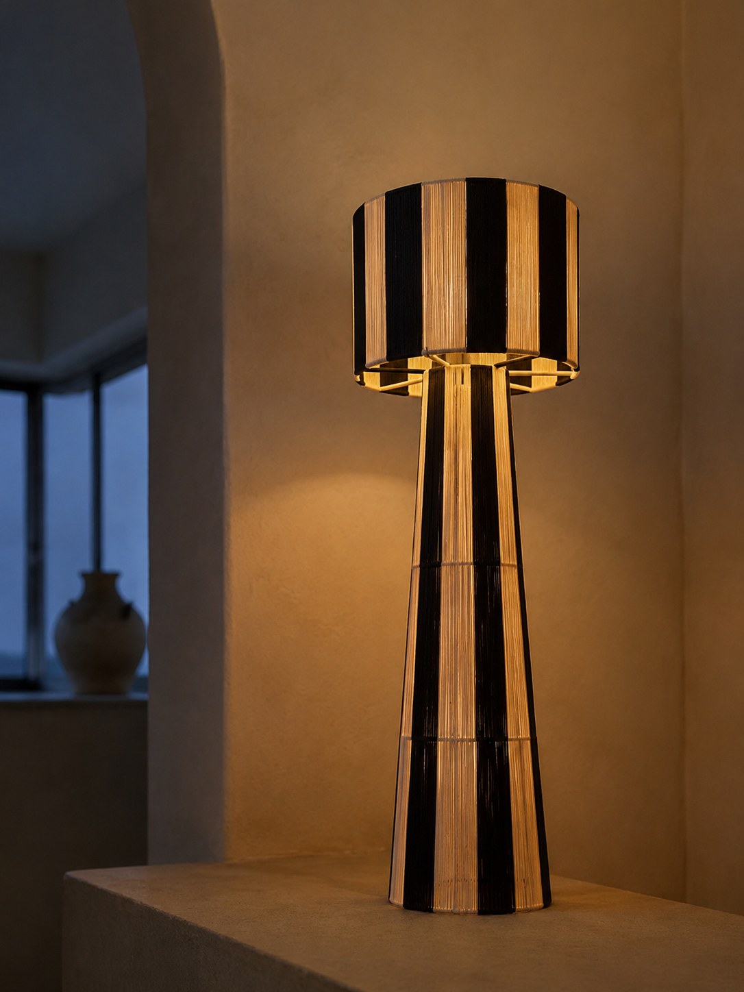 NARA, lampadaire tressé allumé, halo ambré dans une pièce sombre